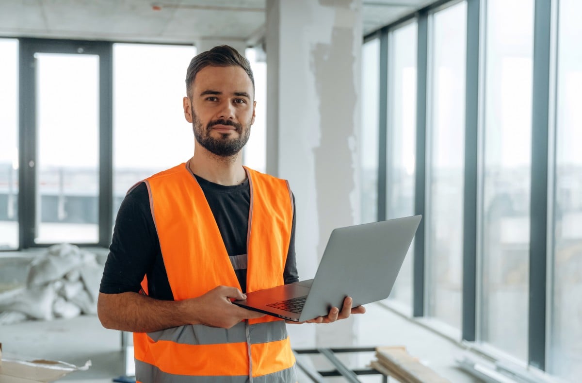 Field service technician using a laptop on-site, representing mobile CRM usage with Workiz software.